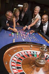 Group of people in casino playing roulette and smiling (selective focus)
