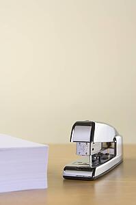 A Silver Stapler And A Pile Of Paperwork