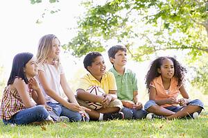 Five young friends sitting outdoors with soccer ball