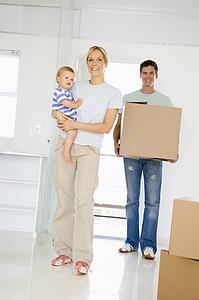 Family with box moving into new home smiling