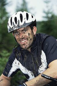 Man outdoors sitting on bicycle dirty and smiling (selective focus)