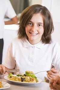 Student in cafeteria eating lunch (selective focus)