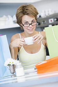 Young woman sitting at a table taking a break from shopping and drinking tea