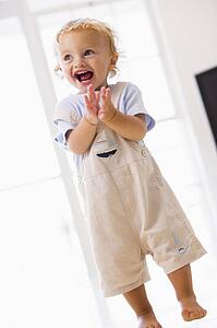 Young boy standing indoors applauding and smiling