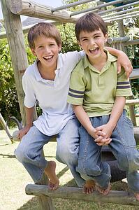 Two young male friends at a playground smiling