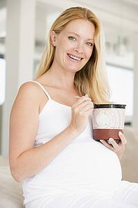 Pregnant woman with bucket of ice cream smiling