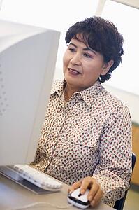 Woman at computer smiling and looking at monitor (high key)
