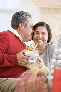 Middle Aged Couple Affectionately Sitting And Holding Christmas Present
