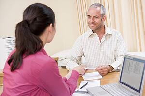 Doctor with laptop and man in doctor's office smiling