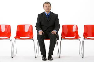 Businessman Sitting In Row Of Empty Chairs 