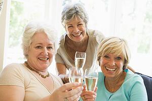 Three women in living room drinking champagne and smiling