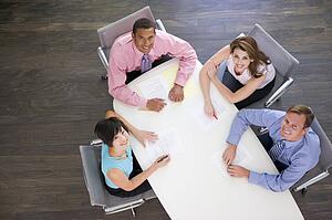 Four businesspeople at boardroom table smiling