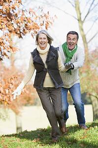 Senior couple outdoors running around and smiling (selective focus)