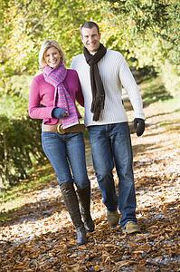 Couple outdoors walking on path in park smiling (selective focus)