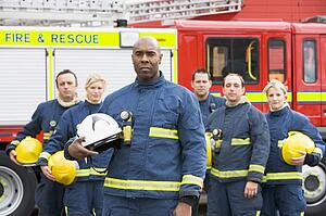 Six firefighters standing by fire engine
