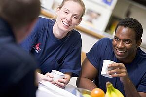 Three firefighters in break room drinking coffee and talking (selective focus)