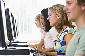 Four people sitting at computer terminals (depth of field/high key)
