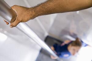 Shot of fireman's hand on a fire pole with firewoman at bottom (selective focus)