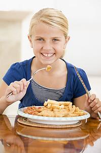 Young girl indoors eating fish and chips smiling
