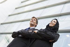 Two businesspeople standing outdoors by building smiling (selective focus)