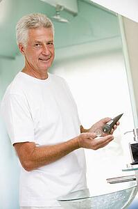 Man in bathroom applying aftershave and smiling