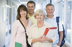 Four people standing in corridor with books (high key)