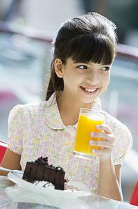 Young girl at restaurant eating dessert and smiling (selective focus)