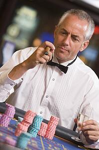 Man in casino playing roulette and smoking cigar (selective focus)
