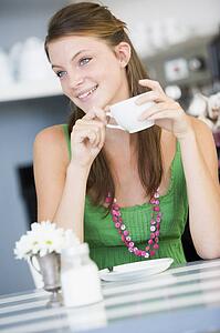 Young woman sitting at a table drinking tea