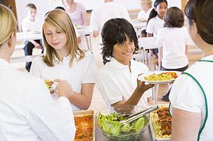 Students in cafeteria line being served by lunch ladies