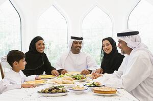 Family sitting at dinner table smiling (high key)