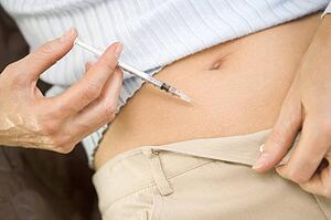 Woman injecting drugs to prepare for IVF treatment (selective focus)