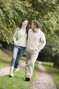 Couple walking outdoors on path in park smiling (selective focus)