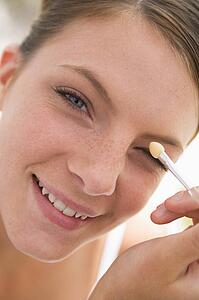 Woman with eyeshadow applicator smiling
