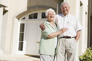 Senior couple standing outside their home