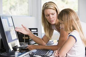 Woman and young girl in home office with computer looking unhappy