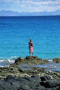 Woman outdoors standing on large rocks Oceanside