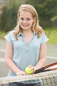 Young girl with racket on tennis court smiling