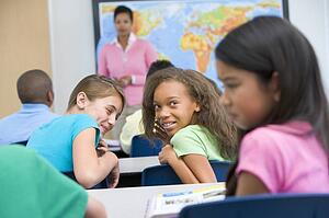 Students in class bullying student with teacher in background (selective focus)