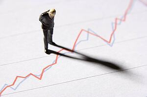 Figurine Of A Businessman Standing On A Line Graph