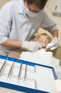 Dentist in exam room with young boy in chair