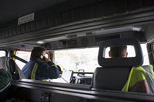 Two firemen in fire engine with one on the radio