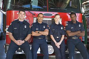 Four firefighters leaning on fire engine