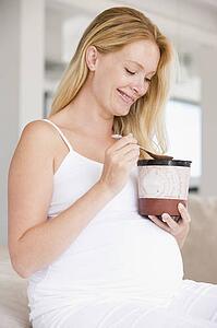 Pregnant woman with bucket of ice cream smiling