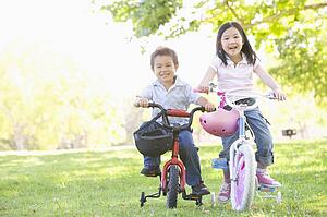 Brother and sister outdoors on bicycles smiling