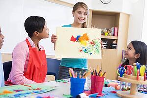 Student showing teacher and classmates her artwork (selective focus)