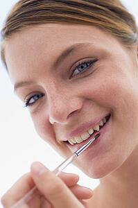 Woman with lipgloss applicator smiling