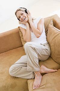 Woman in living room listening to headphones smiling