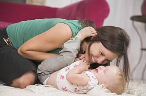 Mother in living room playing with baby smiling