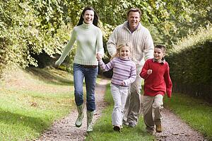 Family running on path outdoors smiling (selective focus)